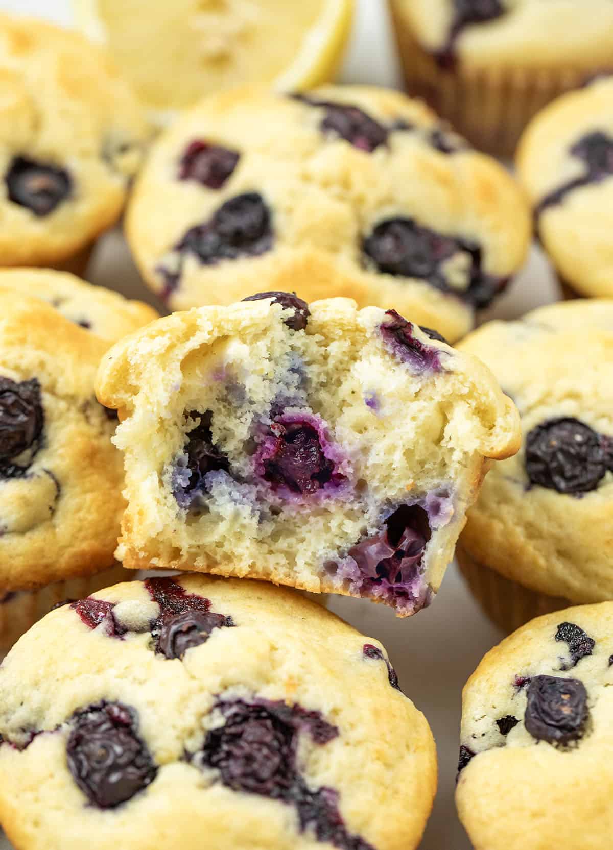 Blueberry Lemon Muffins with one muffin halved resting on top.
