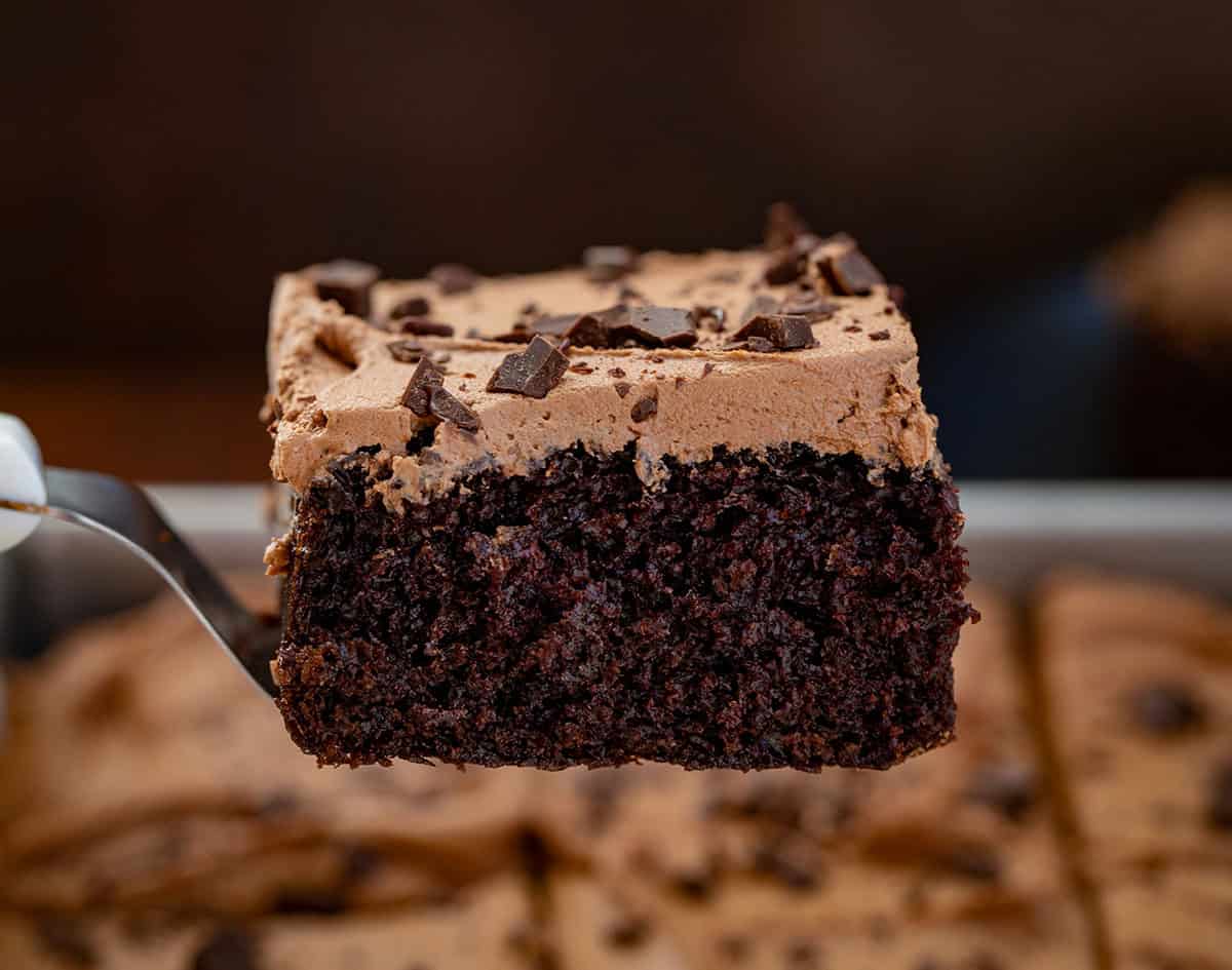 Spatula holding up a piece of Chocolate Sheet Cake with Chocolate Buttercream on top.