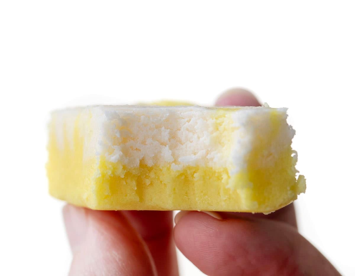 Hand holding a piece of bit into Lemon Creamsicle Fudge.