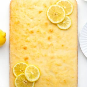 Lemon Sheet Cake on a white table with fresh lemons from overhead.