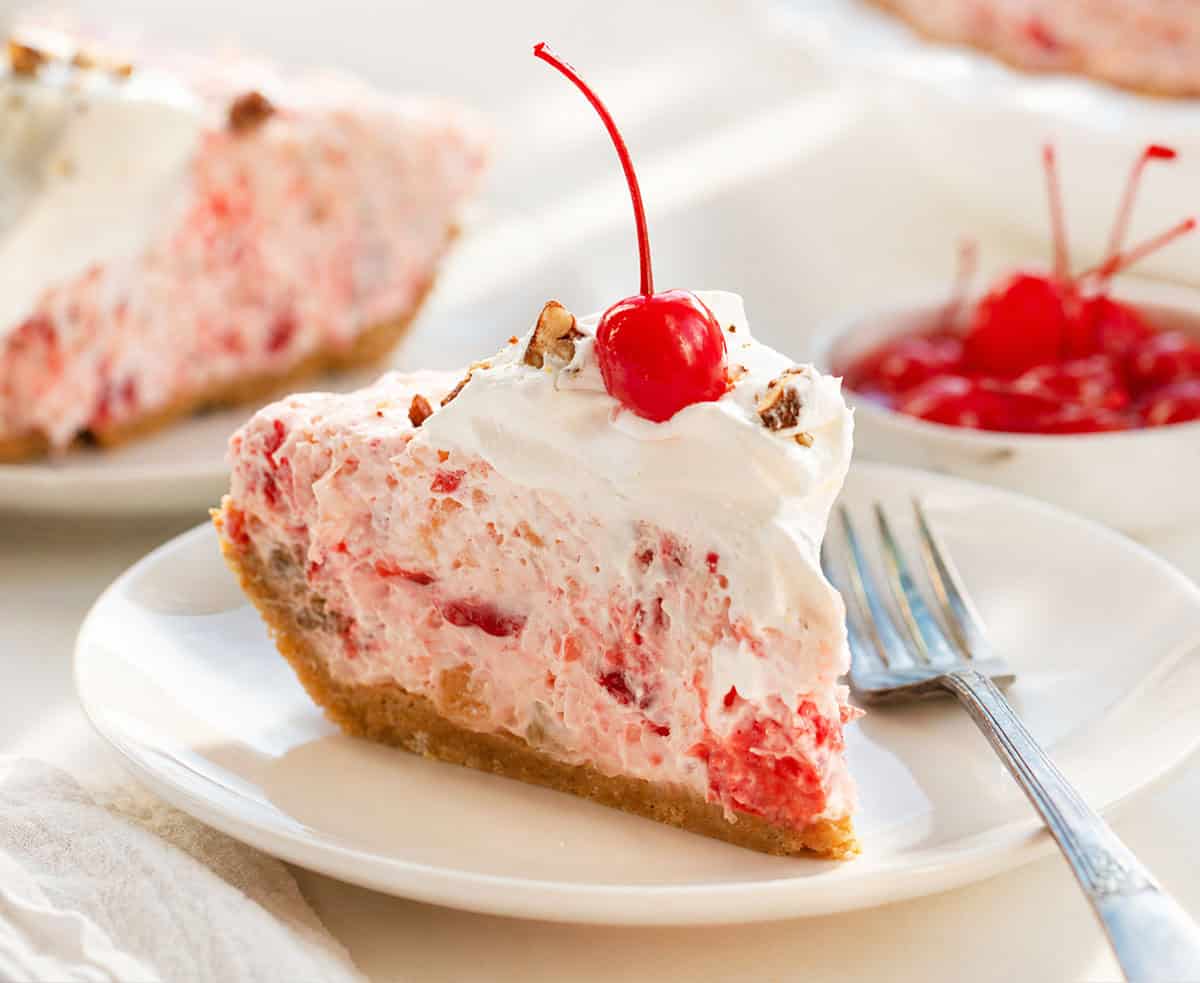 Slices of Millionaire Pie on white plates on a white table.