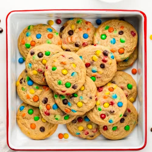 Mini M&M Cookies in a white square pan on a white table from overhead.