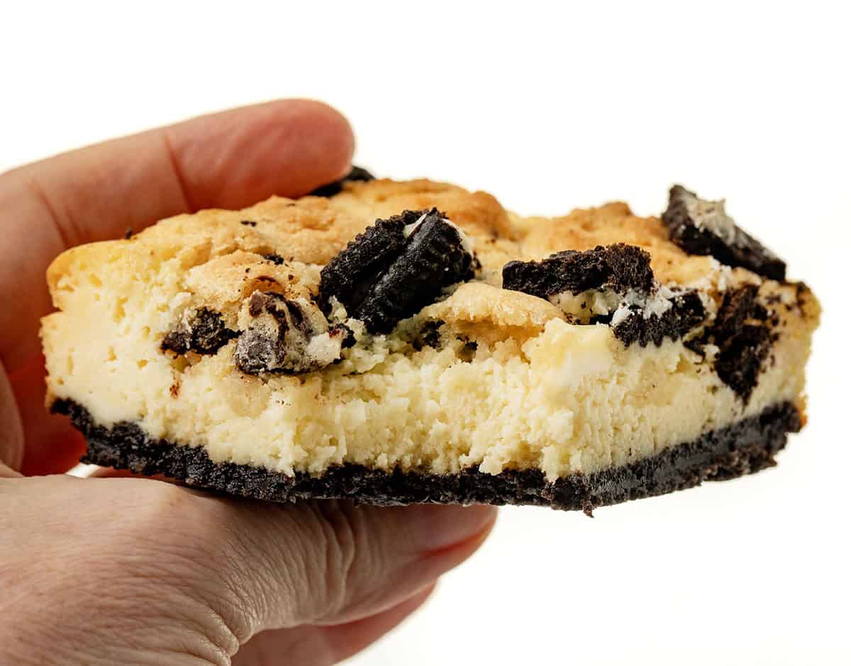 Hand holding a bit into Oreo Chocolate Chip Cheesecake Bar.