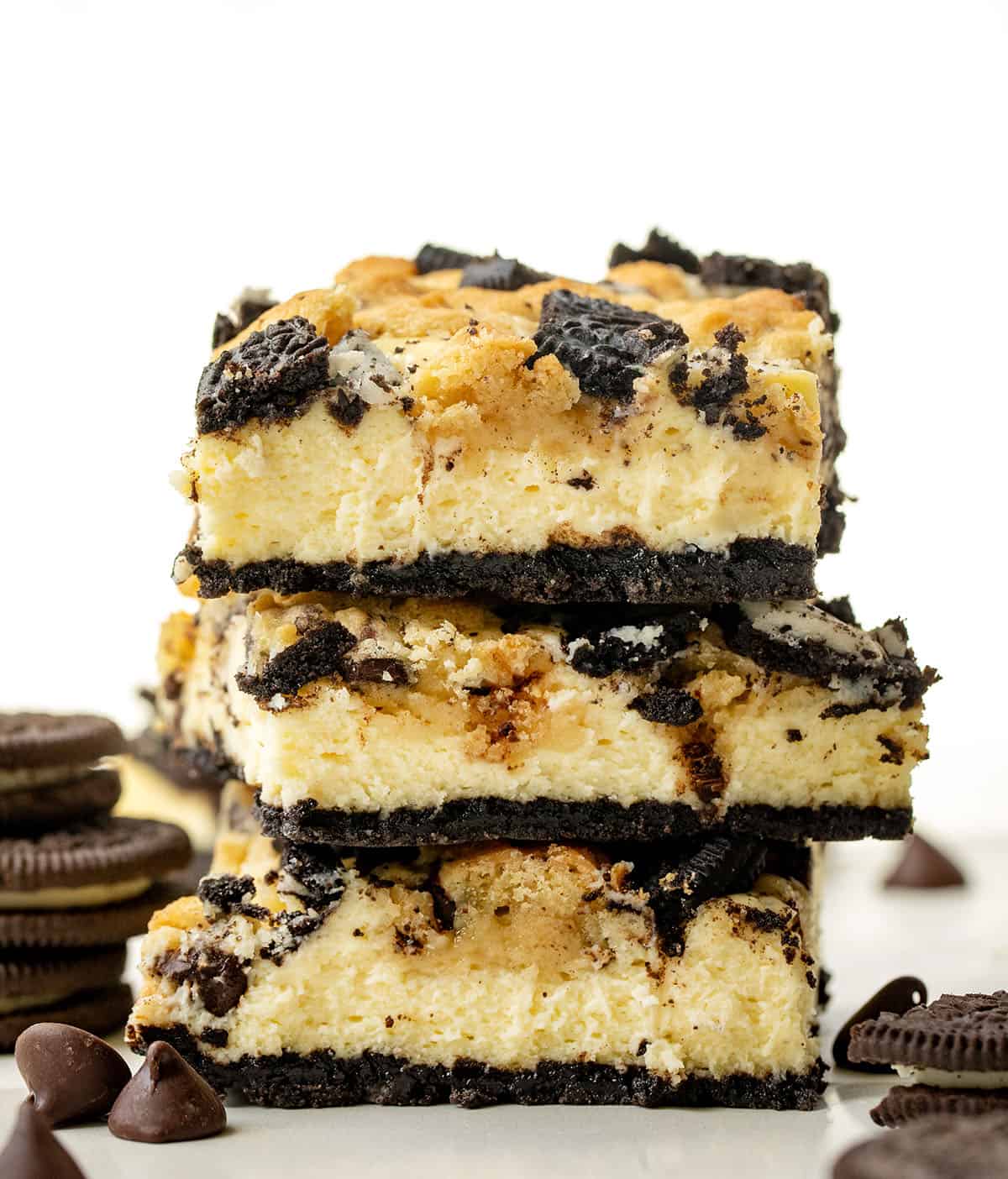 Stack of Oreo Chocolate Chip Cheesecake Bars on a white table.