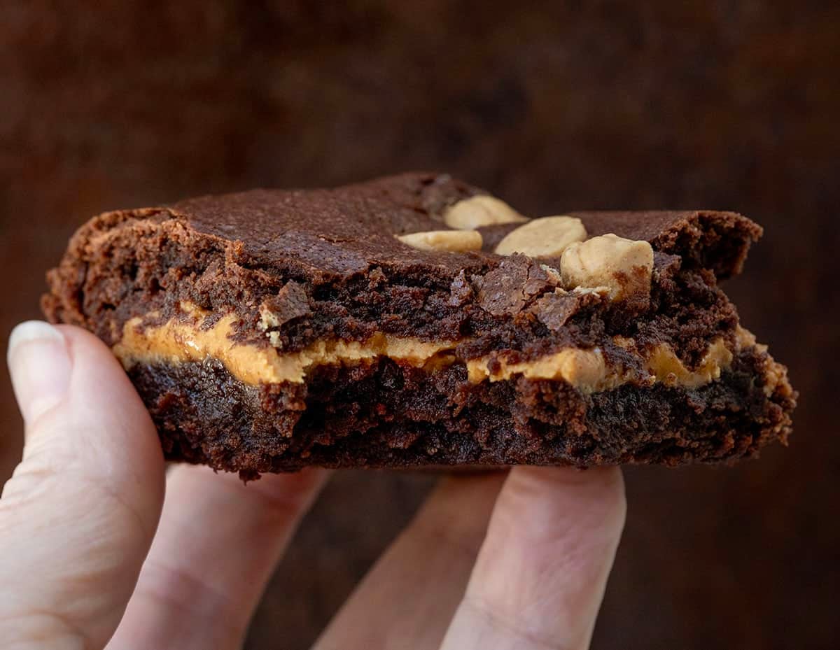 Hand holding a bit into Peanut Butter Stuffed Brownie.