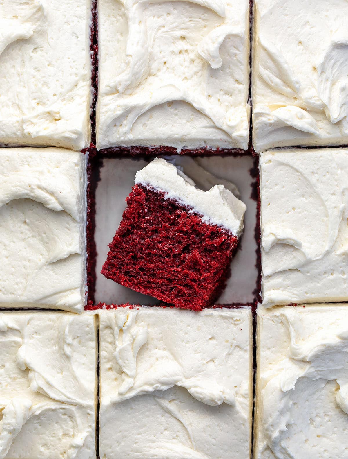 Red Velvet Sheet Cake cut into pieces with the center piece on its side showing the tender texture.