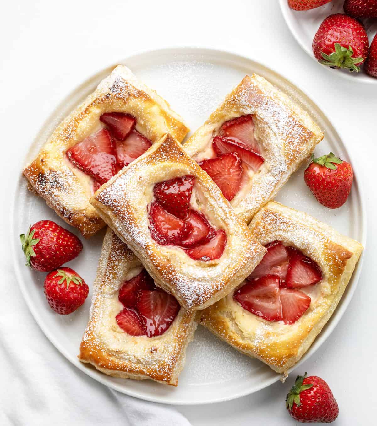 White plate with Strawberry Cream Cheese Danish on it on a white table from overhead.