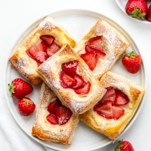 White plate with Strawberry Cream Cheese Danish on it on a white table from overhead.
