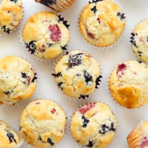 Triple Berry Muffins on a white table with fresh berries from overhead.