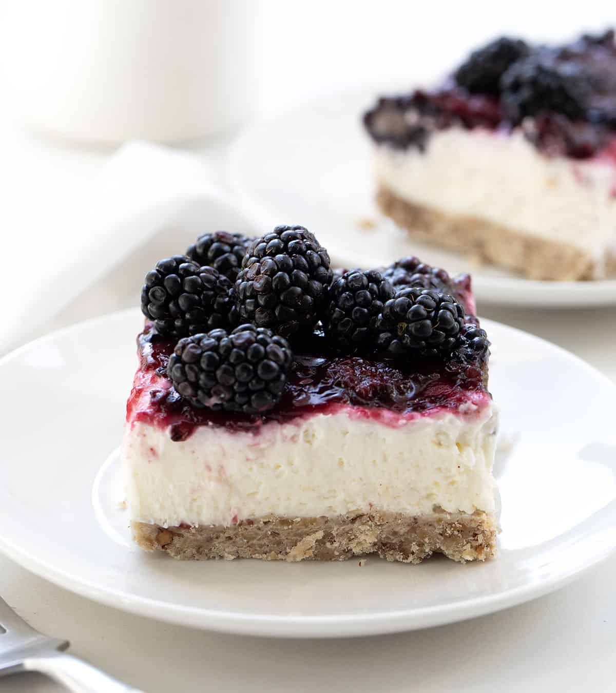 White plates of Blackberry Cream Cheese Bars on a white table.