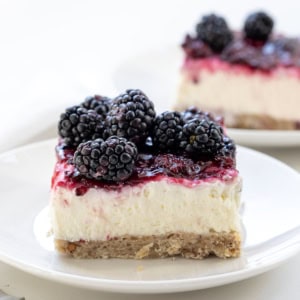 White plates with Blackberry Cream Cheese Bars on them on a white table.