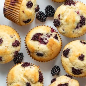 Blackberry Muffins on a white table with fresh blackberries from overhead.