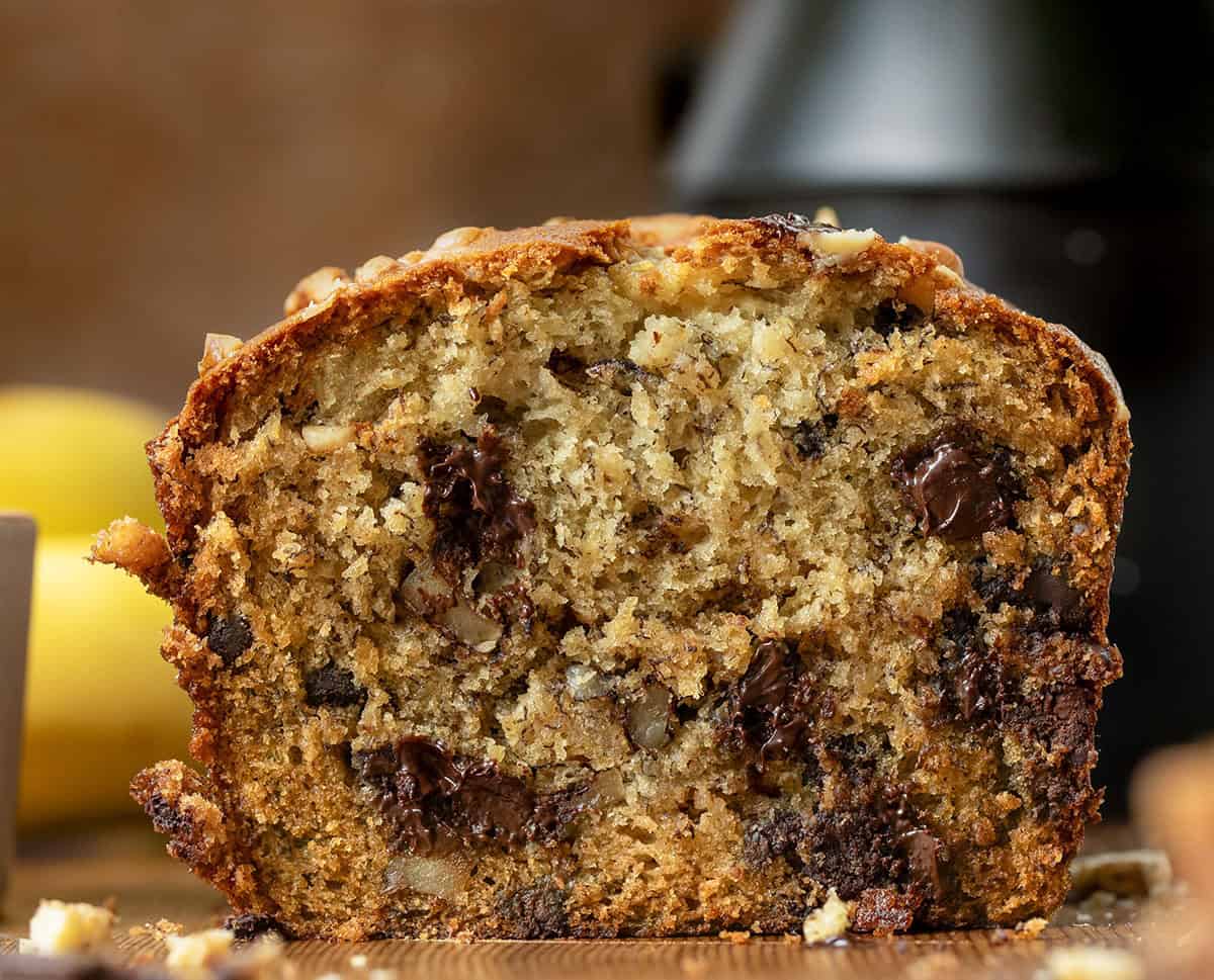 This Chunky Monkey Banana Bread is soft, ultra moist, and loaded with ripe bananas, melty chocolate chunks, and crunchy walnuts in every bite. Itโs a cozy, bakery-style quick bread that leans a little indulgent in the best way! CLose up of a cut into loaf of Chunky Monkey Banana Bread showing the tender crumb of the banana bread.