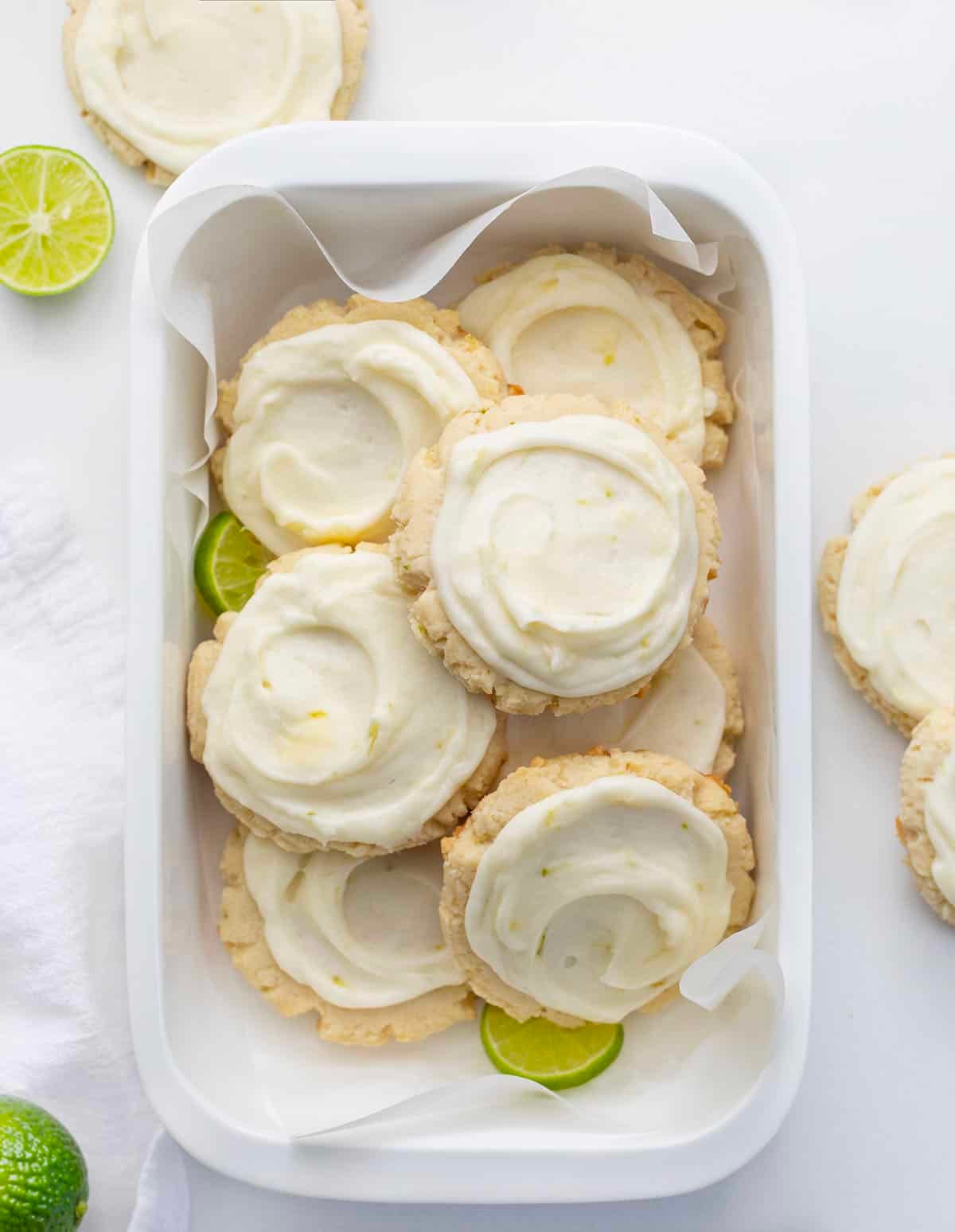 Key Lime Cookies in a white dish on a white table with fresh key limes from overhead.