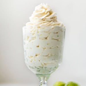 Glass with Key Lime Ermine Frosting piped into it on a white table.