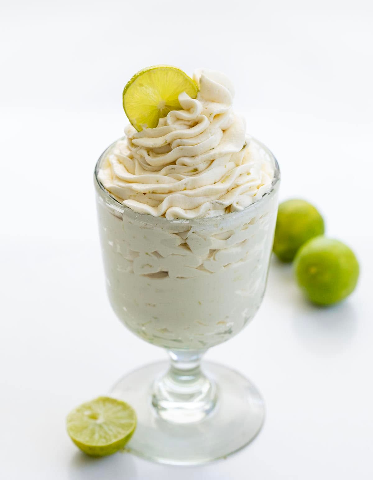 Glass of Key Lime Ermine Frosting with fresh key limes.