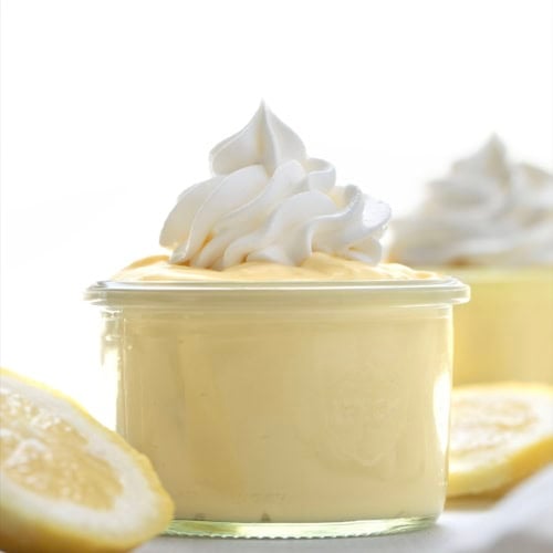 Jars of Lemon Pudding with whipped cream piped on top.