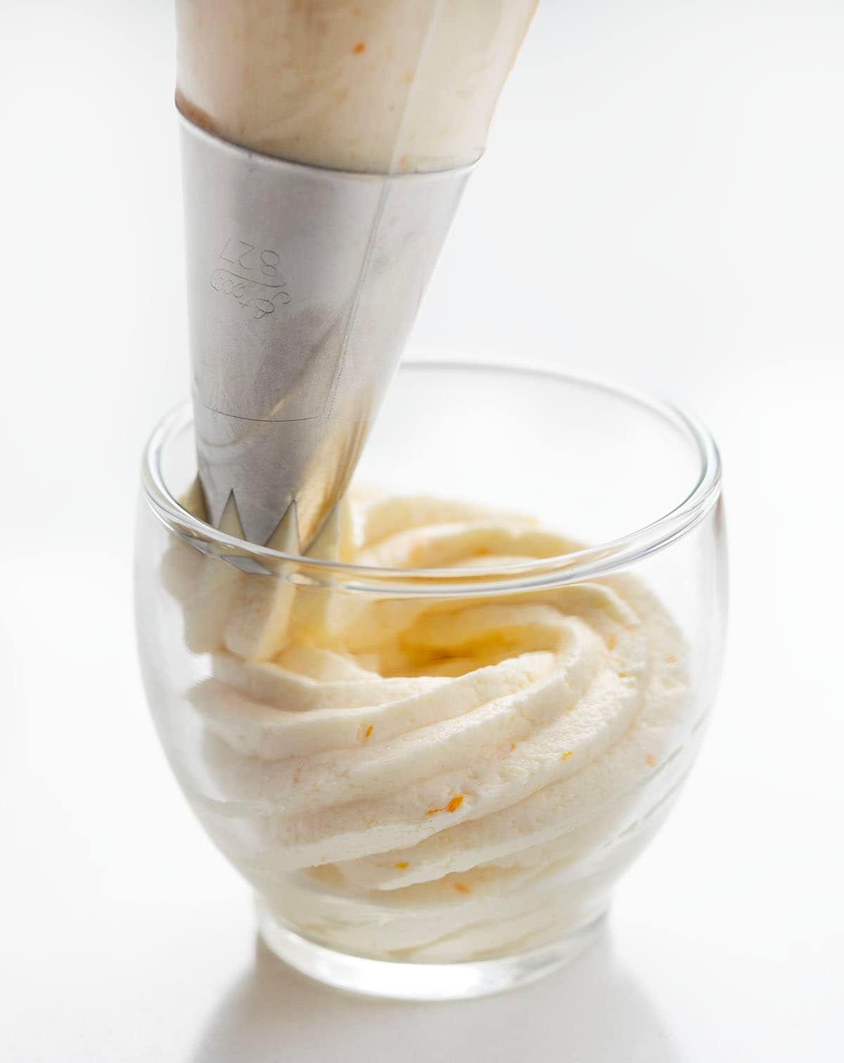 Piping Orange Ermine Frosting into a glass.