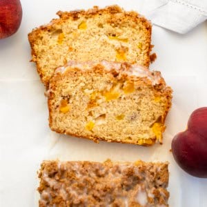 Looking down on a loaf of Peach Cobbler Bread on a white table with a couple of pieces cut and laying flat.