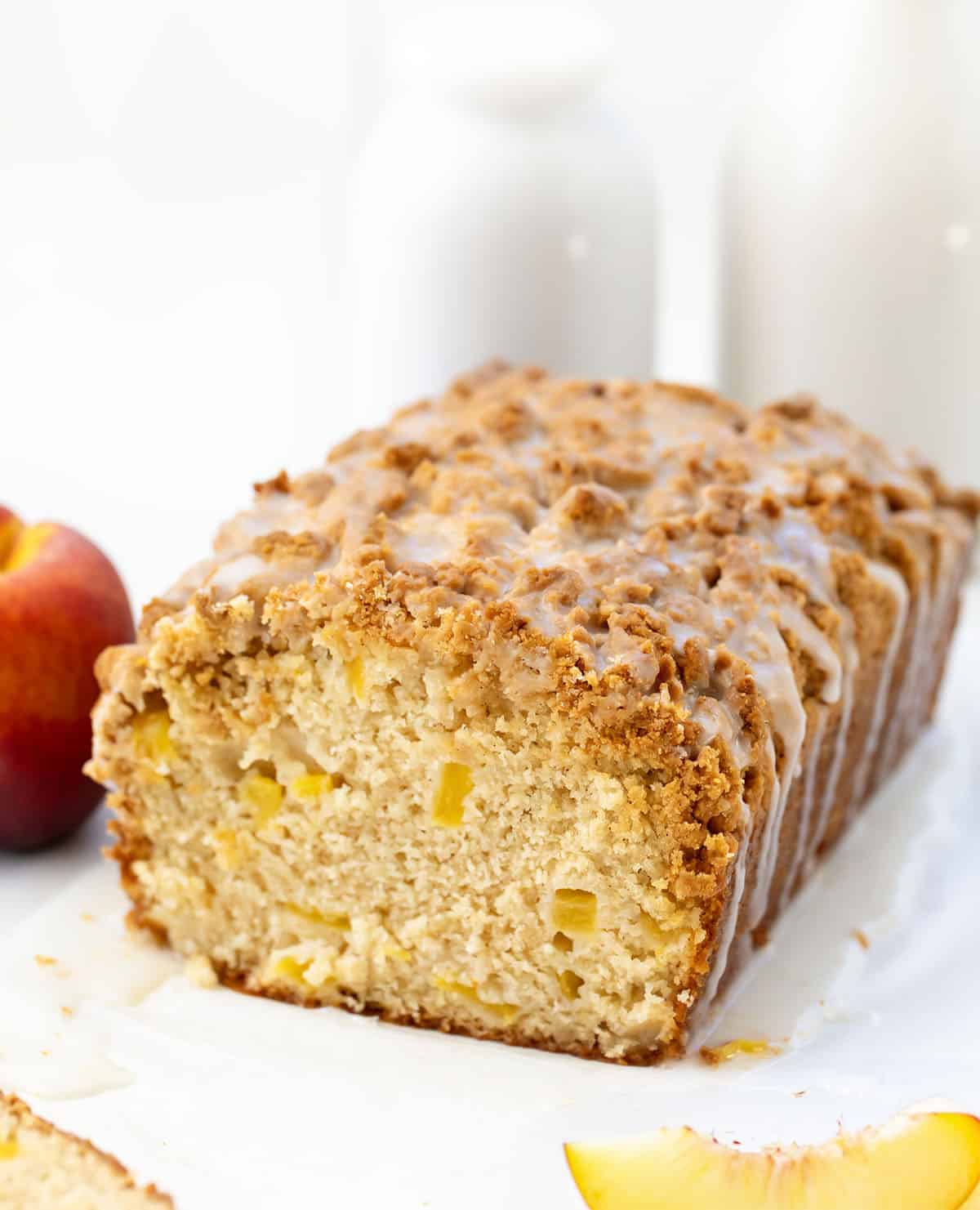 Cut into loaf of Peach Cobbler Bread with fresh peaches and glaze.