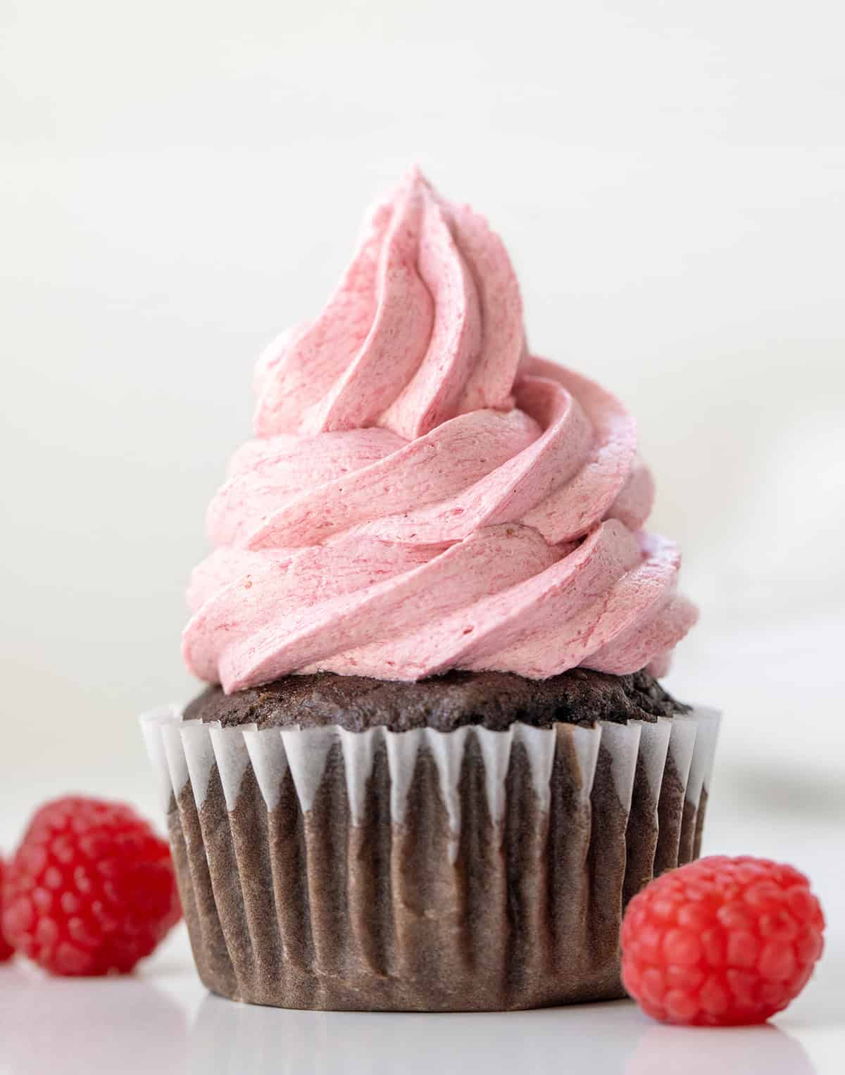 Raspberry Ermine Frosting piped onto a chocolate cupcake close up.