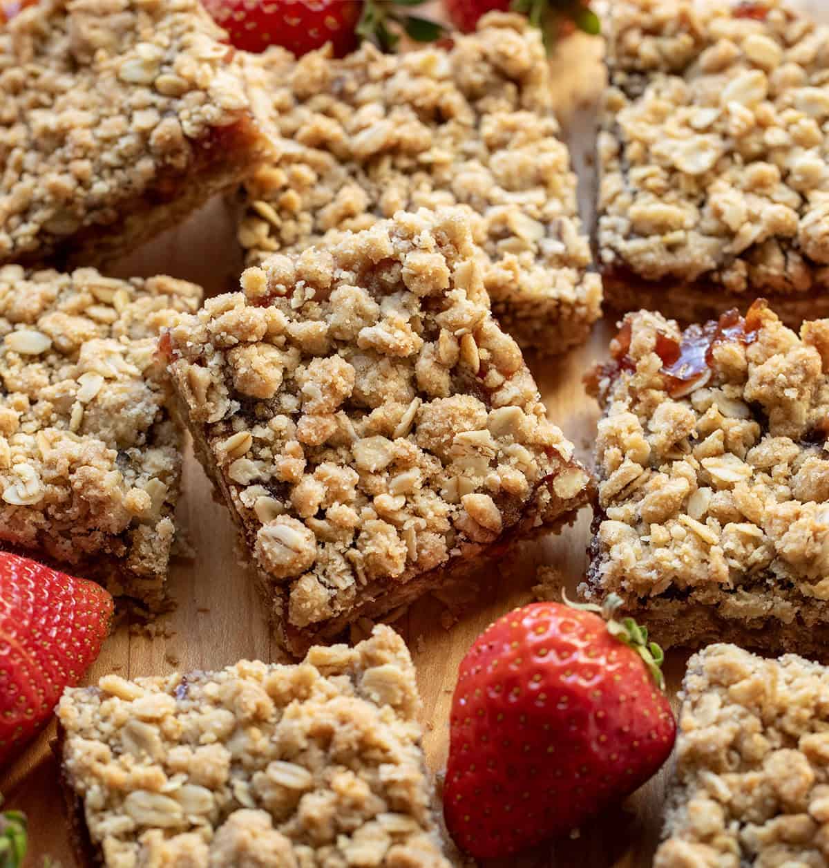 Strawberry Oatmeal Crumble Bars cut up and stacked on each other next to fresh strawberries.