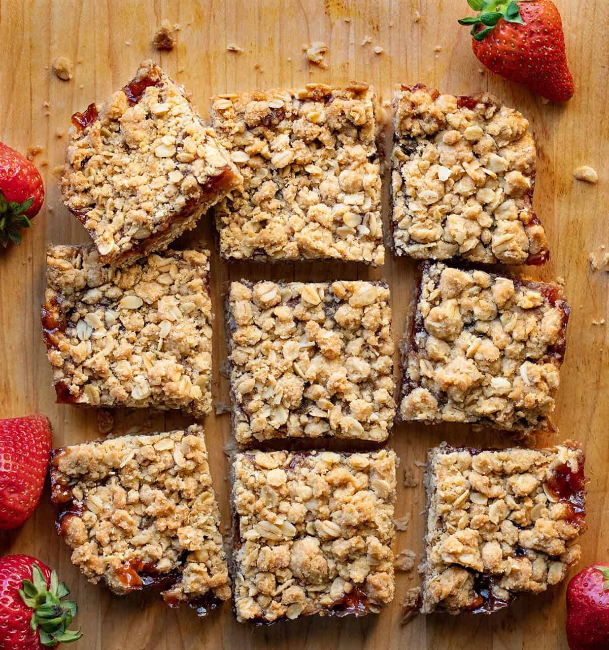 Strawberry Oatmeal Crumble Bars cut into squares on a wooden table from overhead.