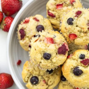 Looking down on Triple Berry Banana Muffins in a bowl on a white table.