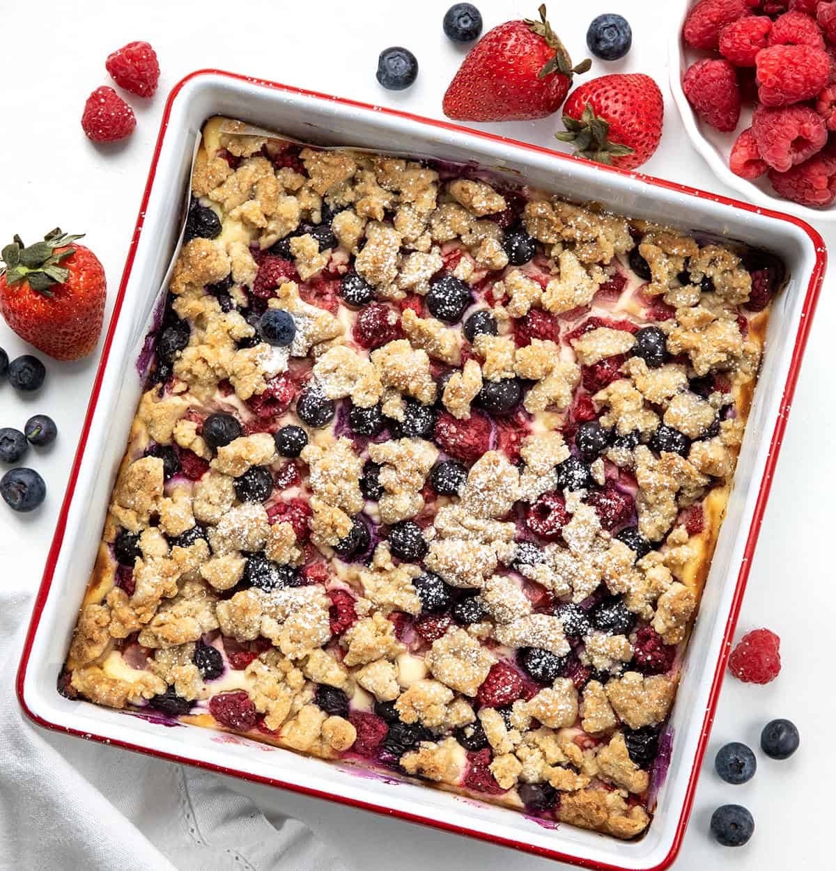 These Triple Berry Cheesecake Bars are a simple,crowd-pleasing dessert made with a buttery graham cracker crust, creamy cheesecake filling, and a mix of fresh blueberries, strawberries, and raspberries!