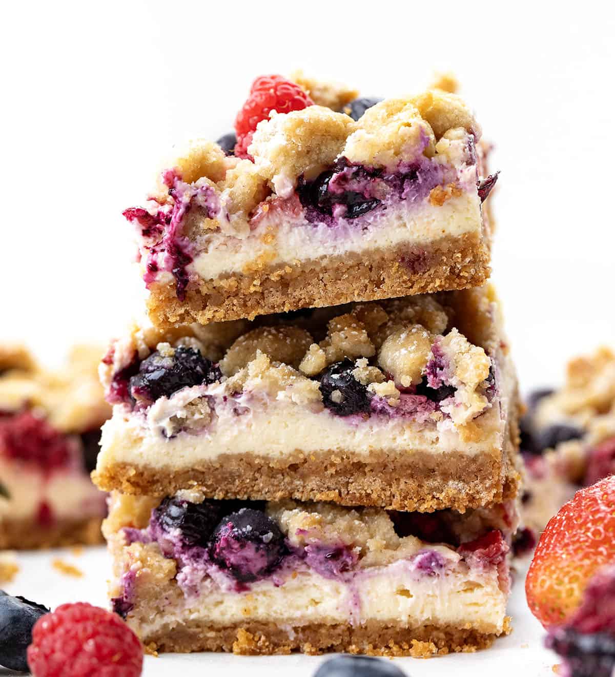 Stack of Triple Berry Cheesecake Bars on a white table.