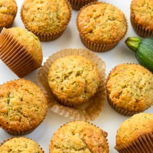 Zucchini Muffins on a white table with a zucchini.