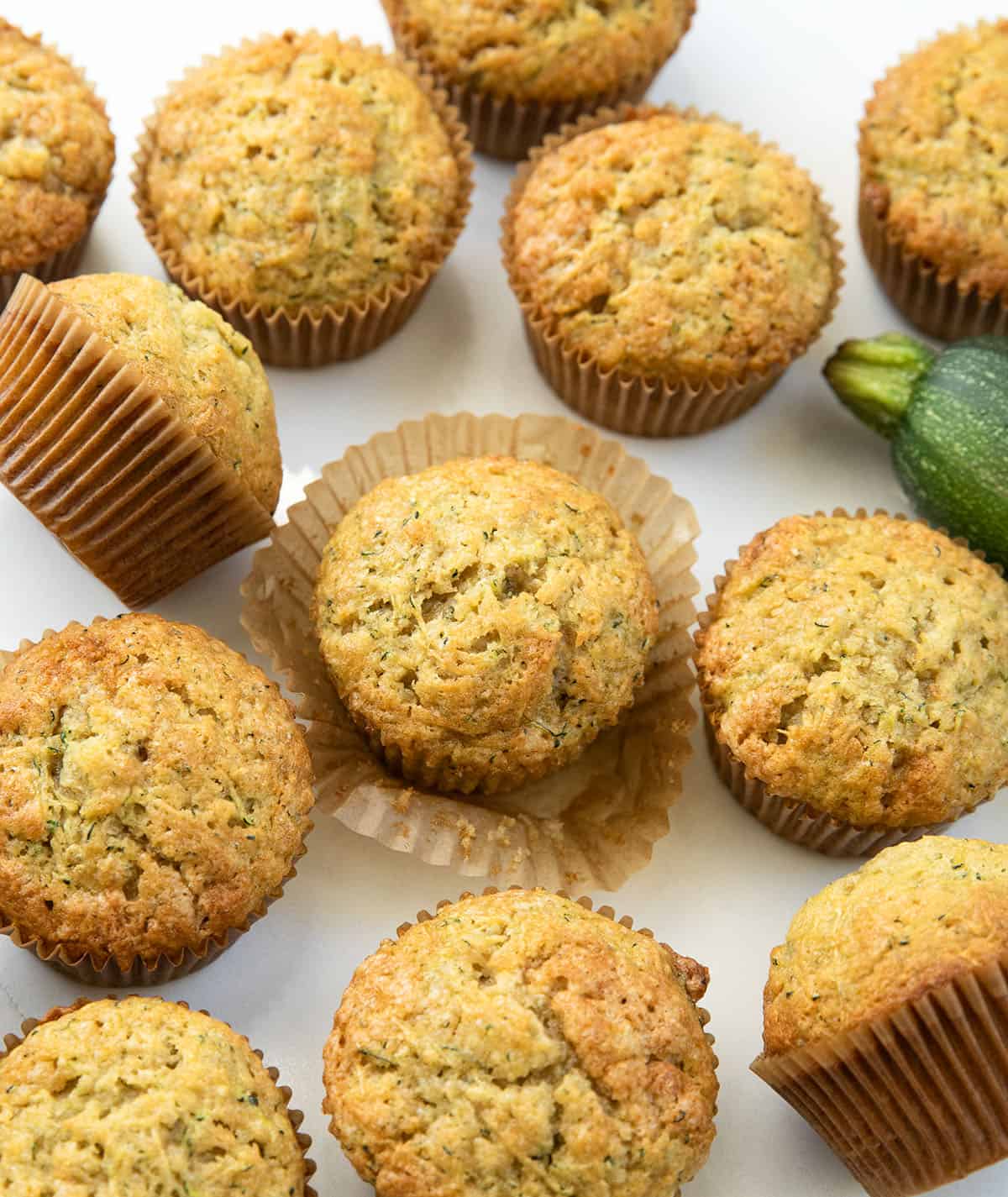 Zucchini Muffins on a white table with a zucchini.