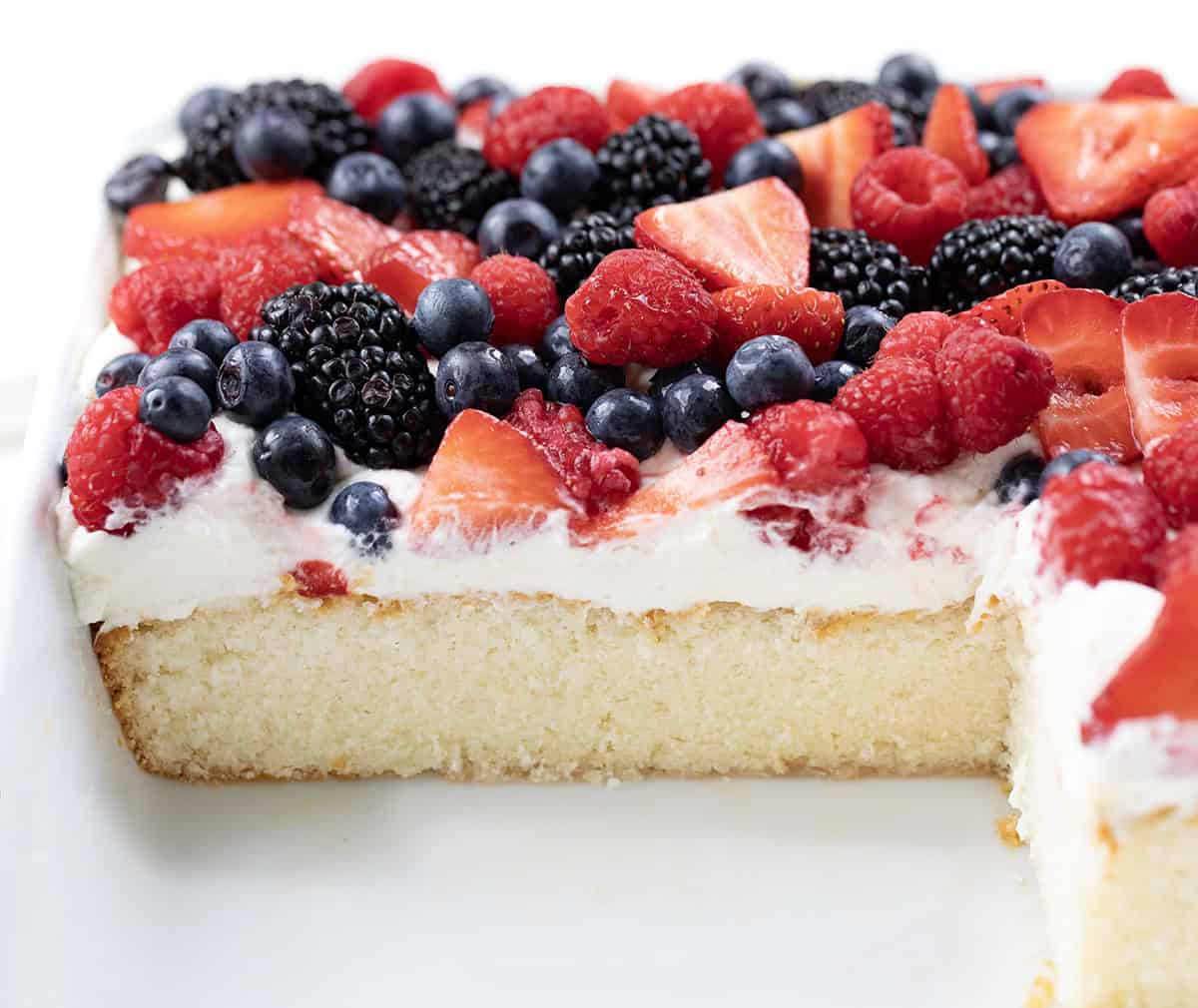Looking into a pan of Berries & Cream Sheet Cake with some of the cake removed.