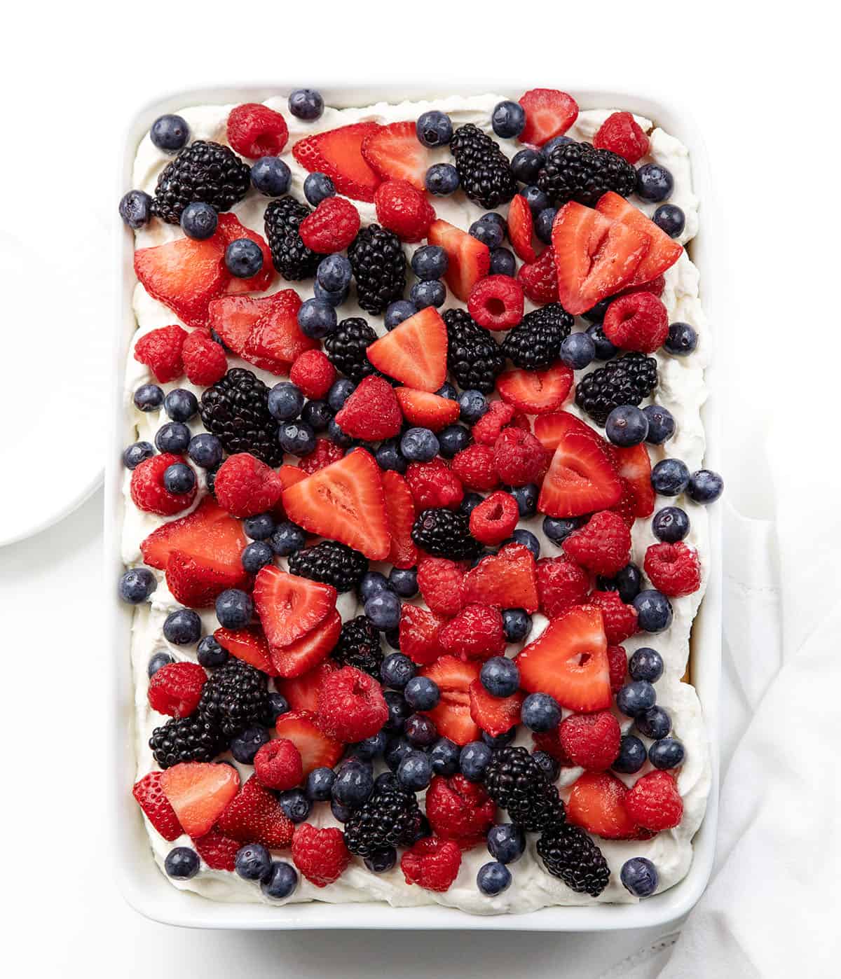 Looking down on a Berries & Cream Sheet Cake on a white table.