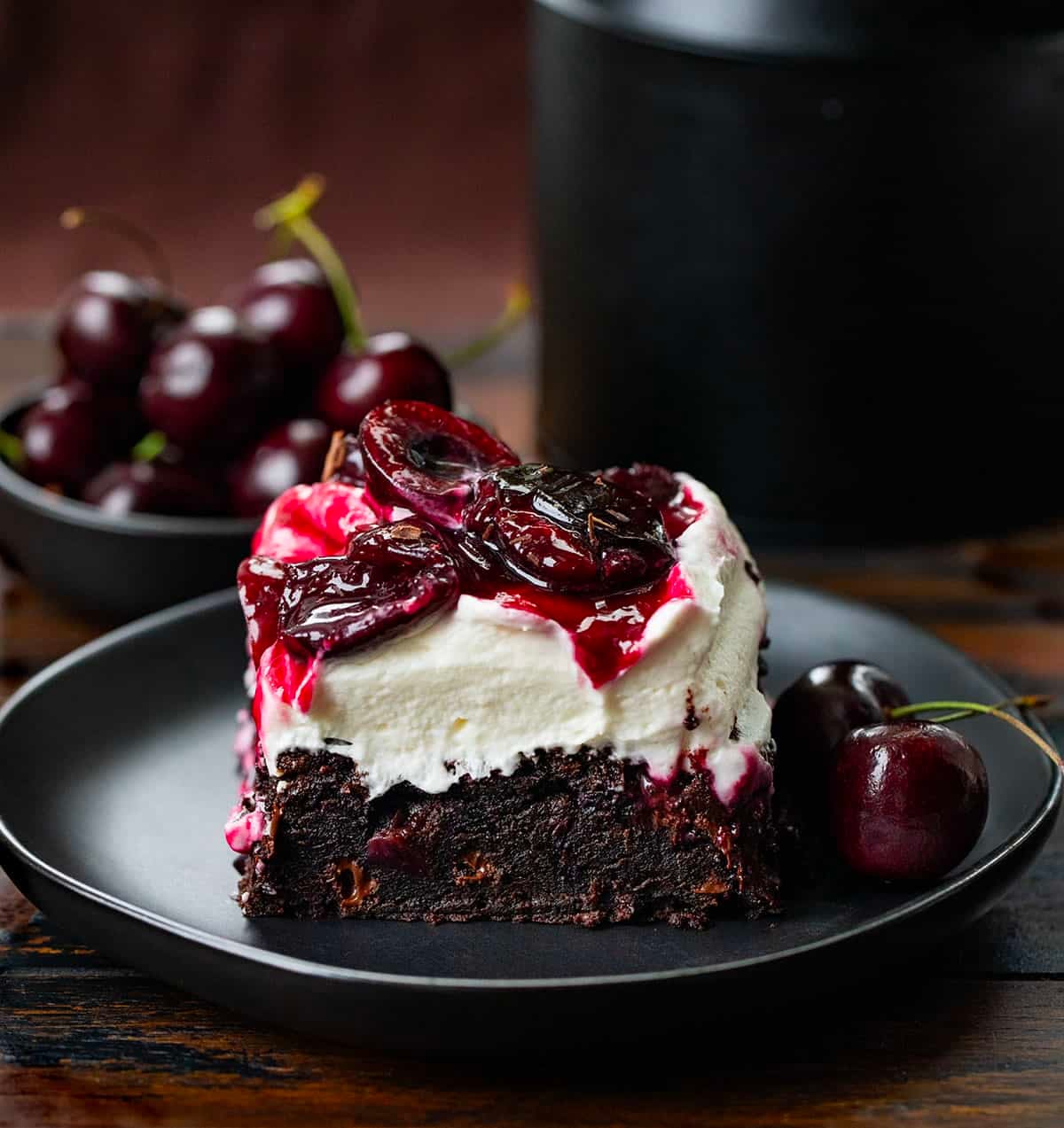 Piece of Black Forest Brownies on a black plate on a wooden table.