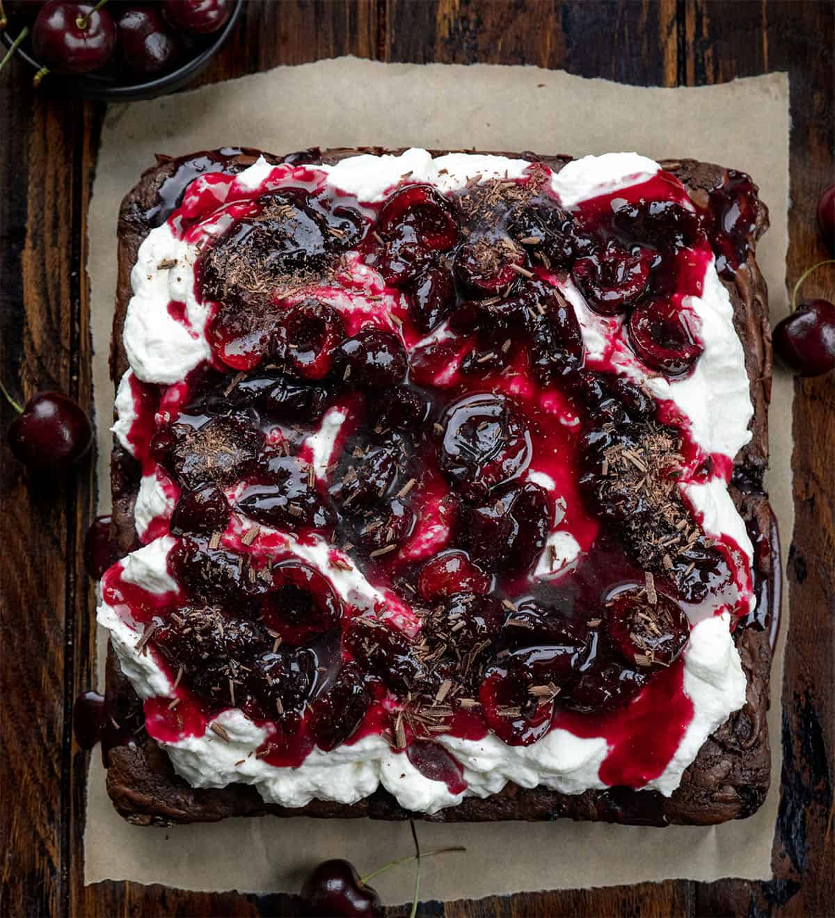 Black Forest Brownies on a piece of parchment on a wooden table from overhead.