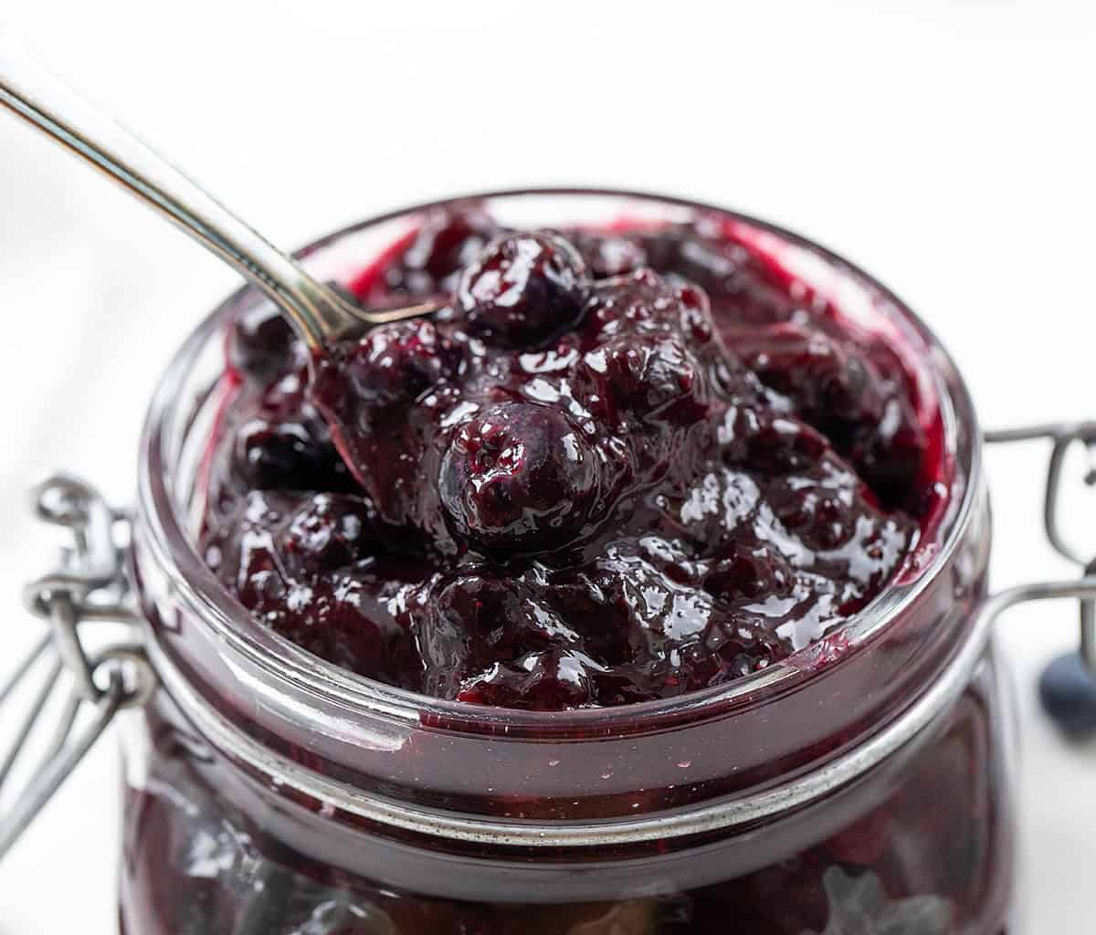 Spoonful of Blueberry Pie Filling being held above the jar.