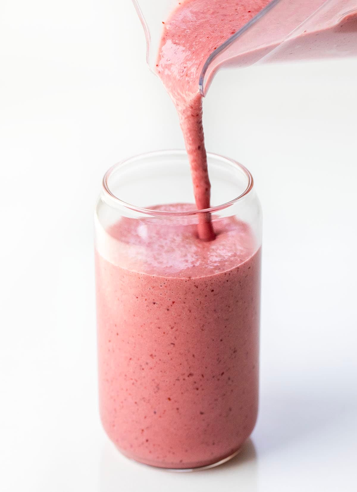 Pouring Cherry Frosted Lemonade into a glass on a white table.