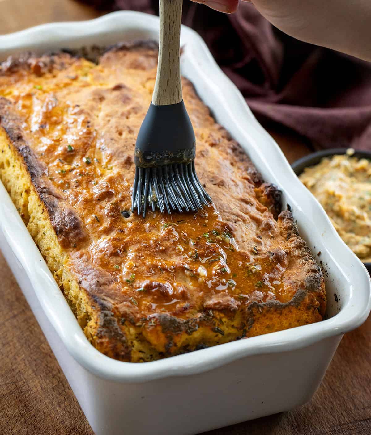 Spreading cowboy butter over a baked loaf of Cowboy Butter Swim Bread.