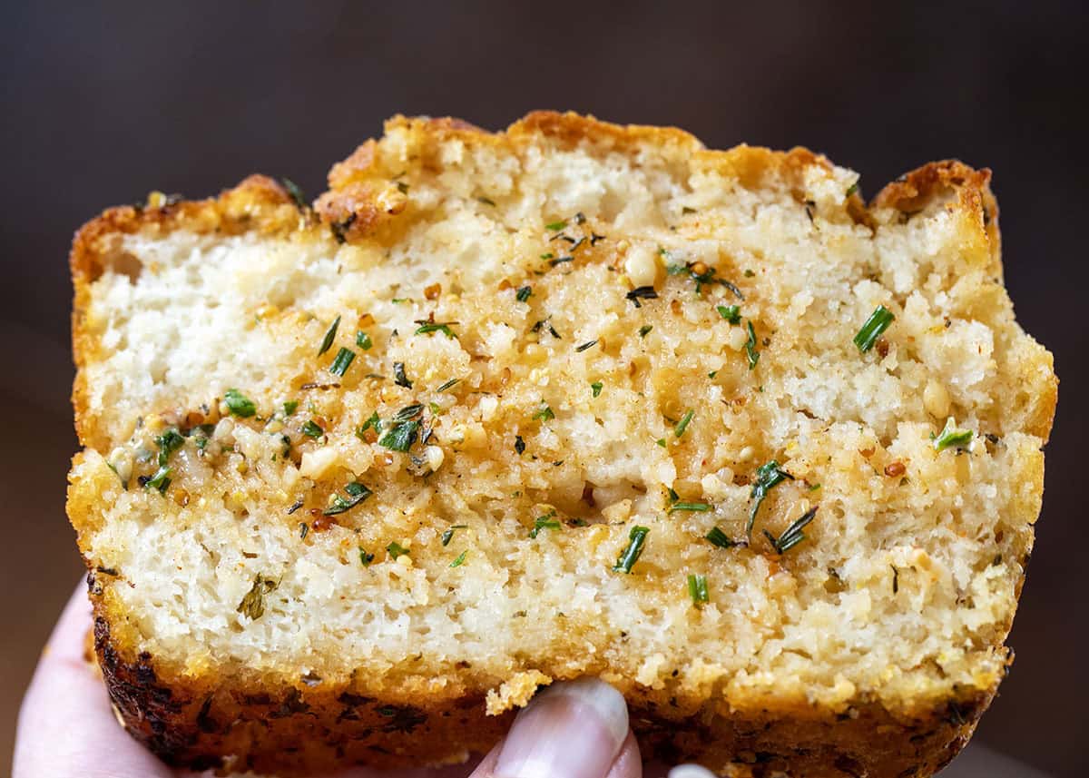Hand holding a piece of Cowboy Butter Swim Bread with cowboy butter on it.