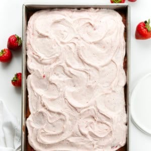 Strawberry Sheet Cake with Strawberry Cream Cheese Frosting on a white table with strawberries from overhead.