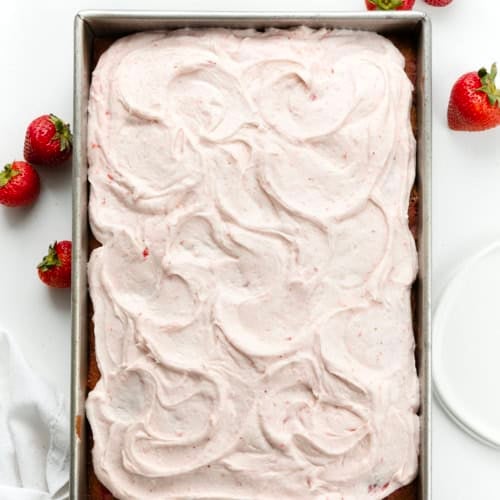 Strawberry Sheet Cake with Strawberry Cream Cheese Frosting on a white table with strawberries from overhead.