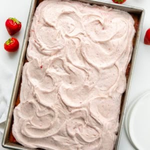Strawberry Sheet Cake with Strawberry Cream Cheese Frosting on a white table with strawberries from overhead.