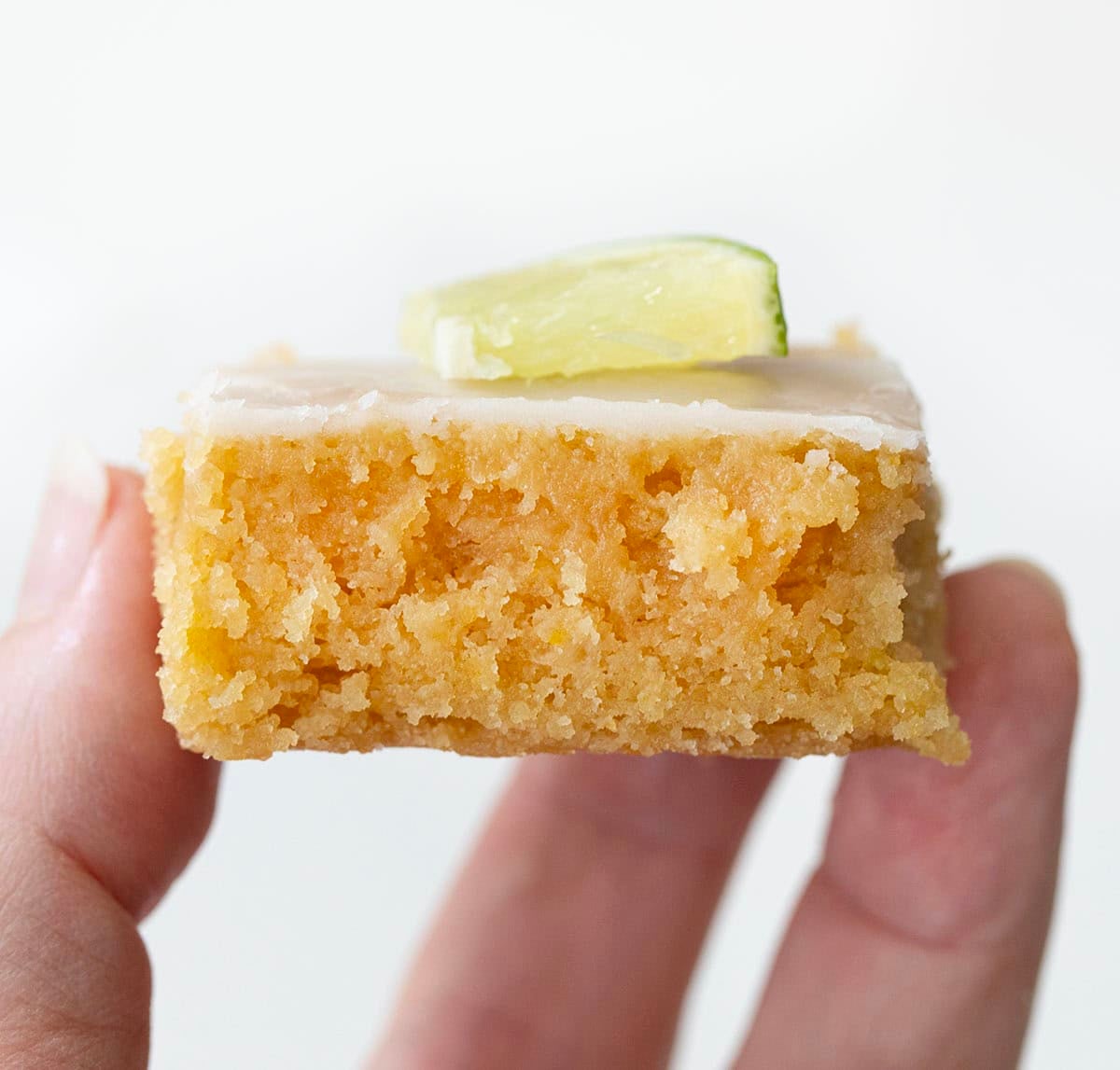 These Lime Brownies are soft, chewy, and bursting with fresh citrus flavor in every bite. Made with brown sugar for a blondie-like texture and finished with a sweet-tart lime glaze, theyโre the perfect balance of rich and refreshing! Hand holding a lime brownie.