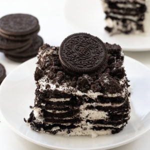 Plate of Oreo Icebox Cake with an Oreo on top on a white table.