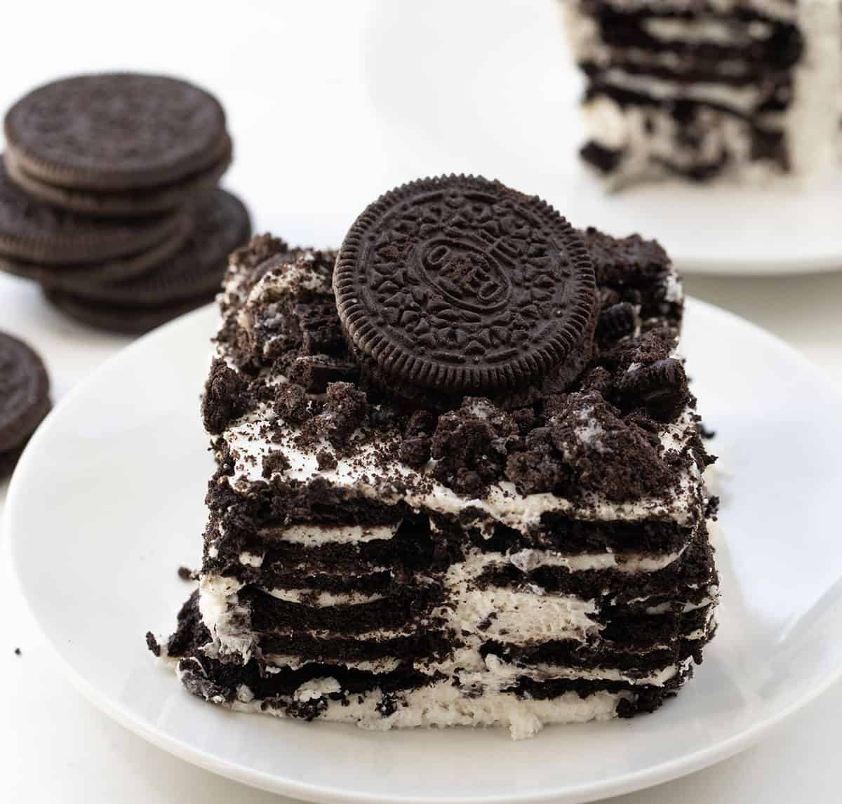 Plate of Oreo Icebox Cake with an Oreo on top on a white table. 