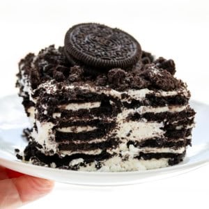 Hand holding a white plate with Oreo Icebox Cake on it.