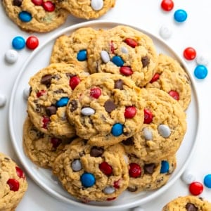 White Plate of Patriotic Monster Cookies on a white table with M&M's around from overhead.
