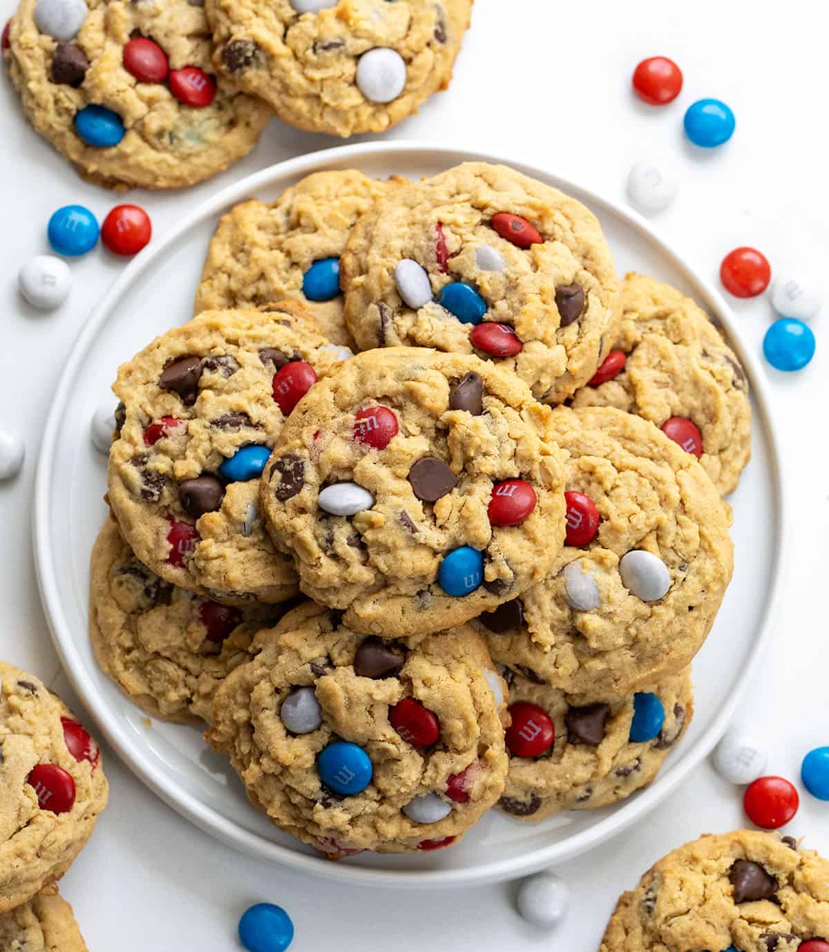 White Plate of Patriotic Monster Cookies on a white table with M&M's around from overhead.