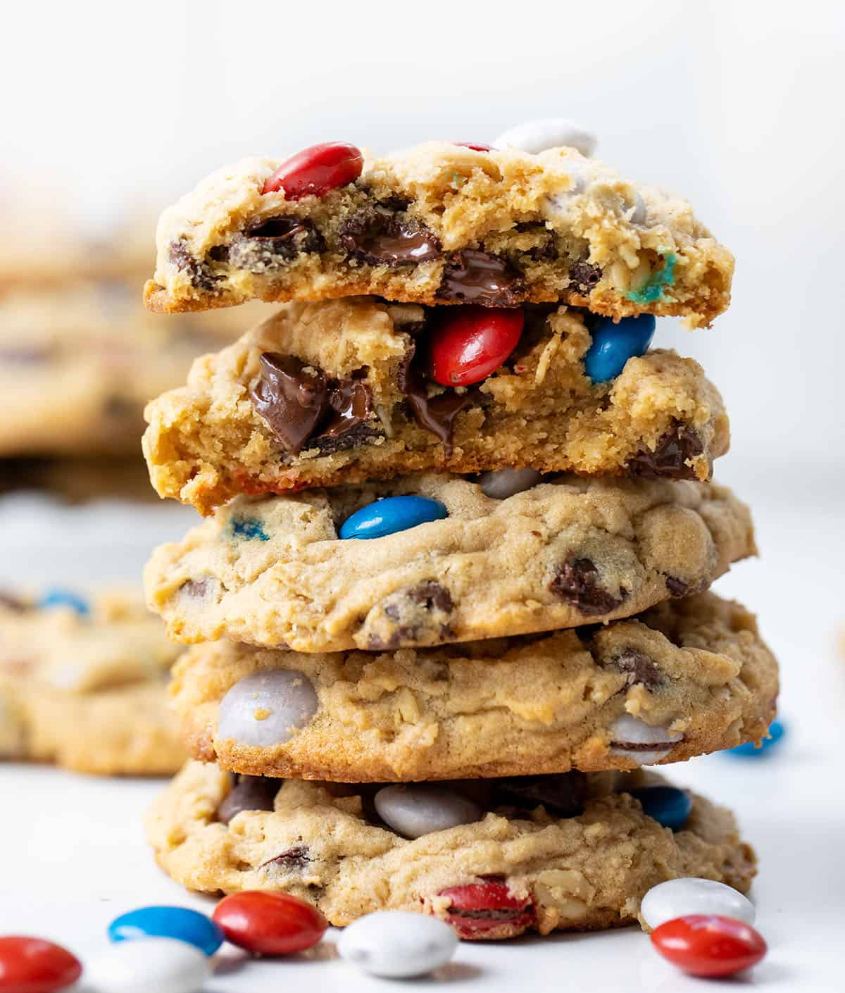Stack of Patriotic Monster Cookies with the top cookie broken in half showing chewy texture.